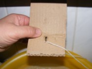Fánk - Egy hullámpapírt derékszögben kettéhajtottam, és az egyik felébe lyukat fúrtam a madzagnak.